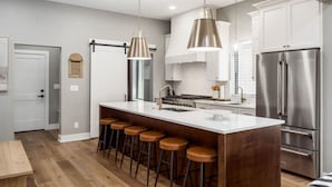 A modern kitchen with a large island, stainless steel appliances, and pendant lighting. - New Build Hot Tub Dtown ShortNorth (Columbus)