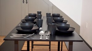 A dining table set with multiple black bowls, silverware, and a spoon. - Houston Home by NRG Stadium & Downtown (Houston)