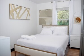 A neatly arranged bedroom with a bed, a bedside table, a wardrobe, and a window with curtains. - Houston Home by NRG Stadium & Downtown (Houston)