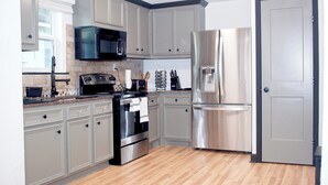 A modern kitchen with grey cabinets, stainless steel appliances, and a wooden floor. - Houston Home by NRG Stadium & Downtown (Houston)