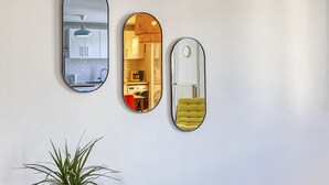 Trois miroirs ovales sont accrochés à un mur et reflètent différents espaces intérieurs.