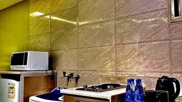 Cocina compacta con microondas, refrigerador y estufa.