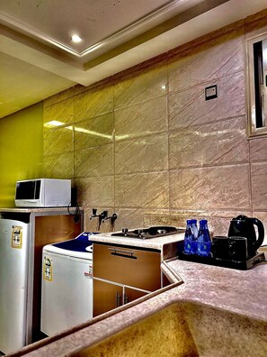 A compact kitchen with a microwave, refrigerator, and stove. - Manazel Aldana (Abha)
