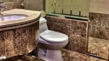 A bathroom with a marble floor, a toilet, a sink with a circular basin, and a mirror.