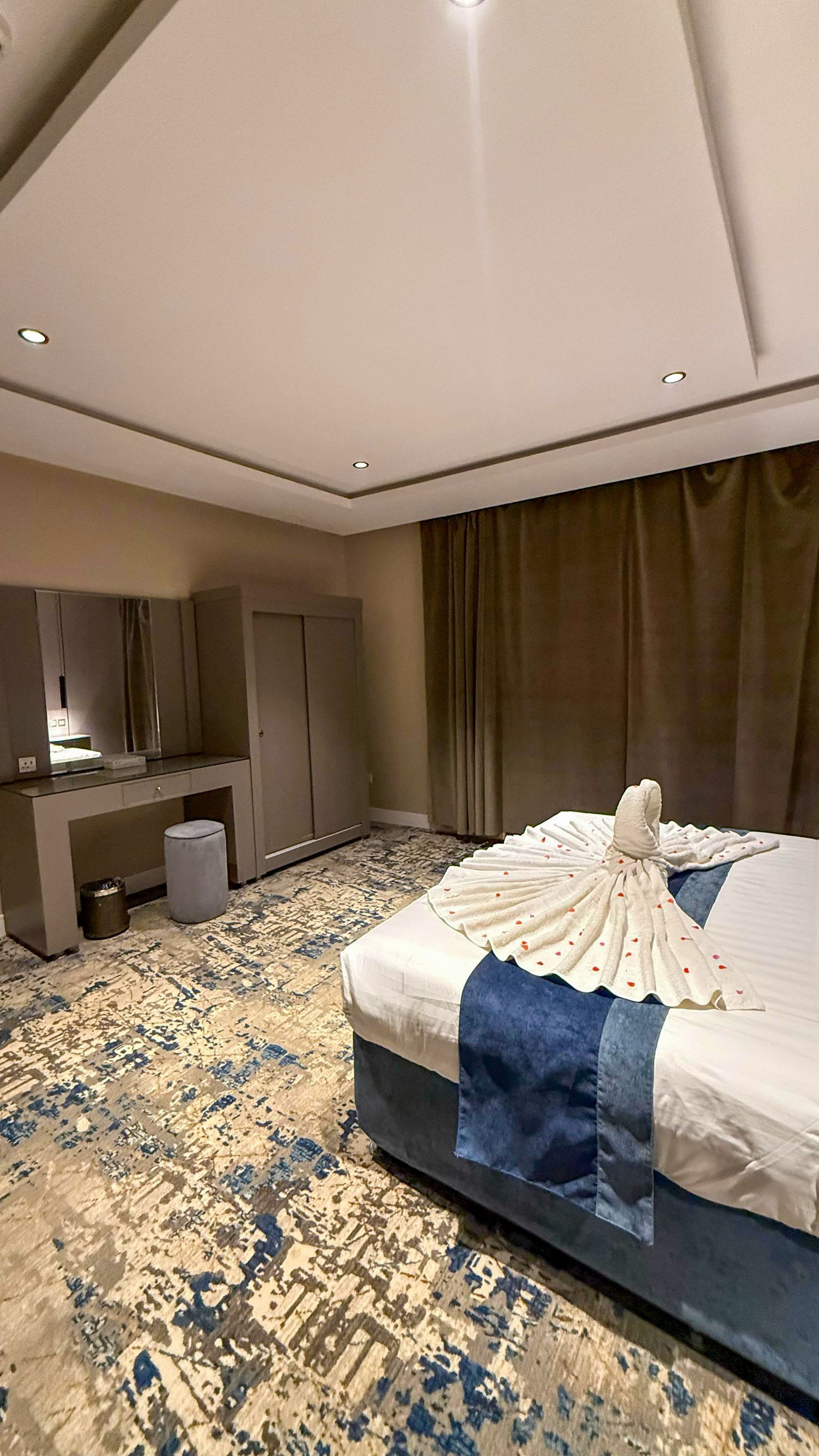 Una habitación de hotel con cama, escritorio, espejo y alfombra.