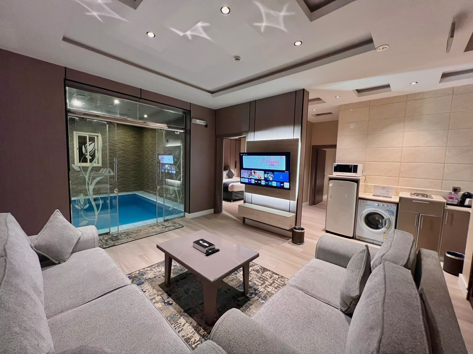 Una sala moderna con piscina, televisor y área de cocina.