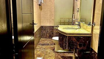 A bathroom with a marble floor, a sink, a toilet, and a mirror.