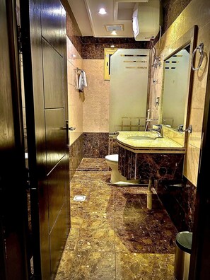 Un baño con piso de mármol, un lavamanos, un inodoro y un espejo.