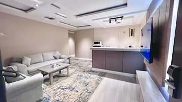 Una sala de estar moderna con un sofá, una mesa de centro y un televisor montado en la pared.