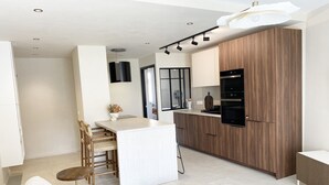 A modern kitchen with a central island, wooden cabinets, and built-in appliances.