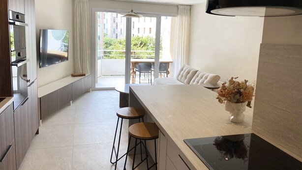 A modern kitchen with a central island, bar stools, a built-in oven, and a large window offering a view of the outdoors.