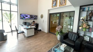 Un espace de bureau moderne comprenant un comptoir d’accueil, plusieurs écrans d’ordinateur, une machine à café et une grande fenêtre.