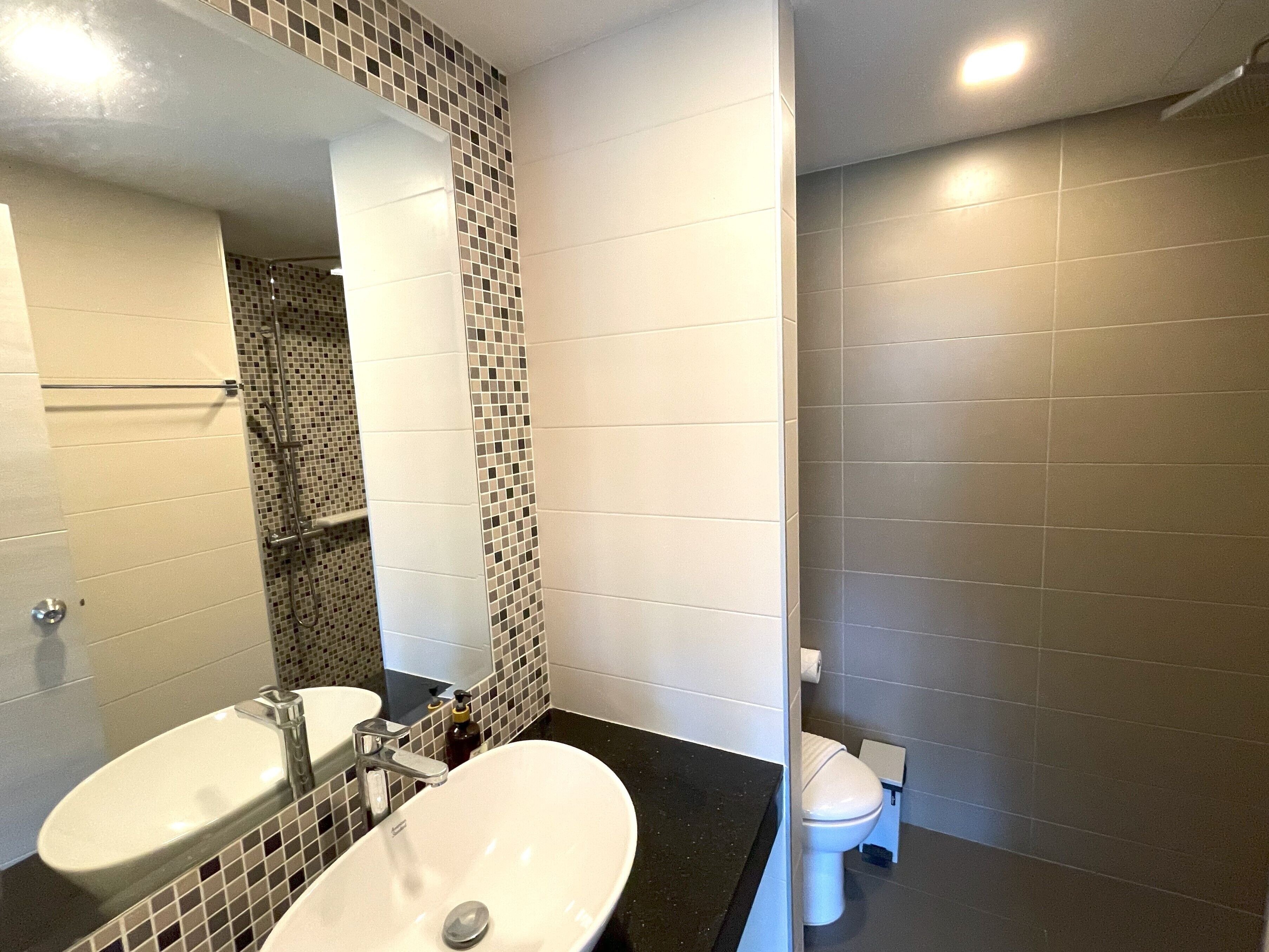 Un baño con dos lavamanos, un espejo y un inodoro.