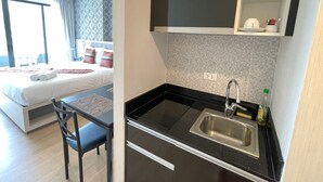 Une chambre d’hôtel de taille réduite, comprenant un lit, une petite kitchenette et un coin repas.