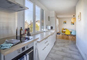 A modern kitchen with a built-in oven, microwave, and a dining area with a table and chairs. - The cozy Charentaise in Angoulême (Angoulême)