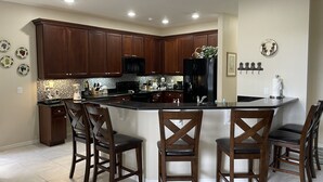 A modern kitchen with dark wood cabinets, a black refrigerator, and a central island with bar stools. - Eagle Dunes gated community. Minutes from Orlando, Disney and Daytona Beach!  (Sorrento)