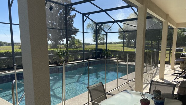 A covered outdoor pool area with a glass enclosure, a table with chairs, and potted plants. - Eagle Dunes gated community. Minutes from Orlando, Disney and Daytona Beach!  (Sorrento)