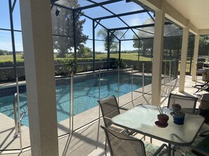 A covered outdoor pool area with a glass enclosure, a table with chairs, and potted plants. - Eagle Dunes gated community. Minutes from Orlando, Disney and Daytona Beach!  (Sorrento)