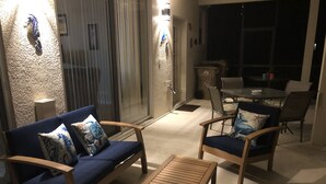 A cozy outdoor seating area with wooden furniture and cushions, a glass door entrance, and a dining table with chairs. - Eagle Dunes gated community. Minutes from Orlando, Disney and Daytona Beach!  (Sorrento)