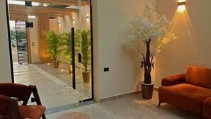 Un espai interior modern amb sostre de vidre, una zona de seients amb sofà i cadires, i una planta en test.