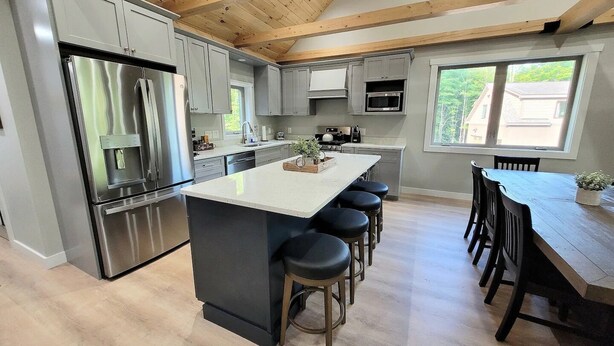 A modern kitchen with a central island, bar stools, and a dining table with chairs.