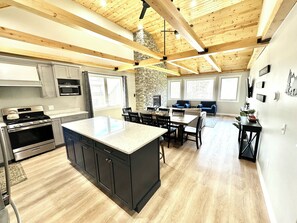 Una cocina amplia con una isla grande, electrodomésticos integrados y una pared decorativa de piedra.