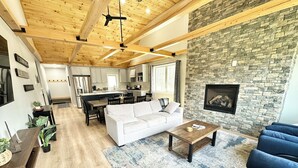 A spacious living area with a white sofa, a coffee table, and a stone fireplace wall.