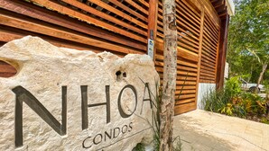 A stone sign with "NHOA CONDOS" for a residential property. - NHOA 108A Lux 2BR Condo Plunge Pool in Aldea Zama (Tulum)