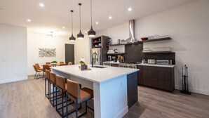 A modern kitchen with a central island, pendant lights, and a dining area with chairs. - Residence 3: The Villas At Troon North (Scottsdale)