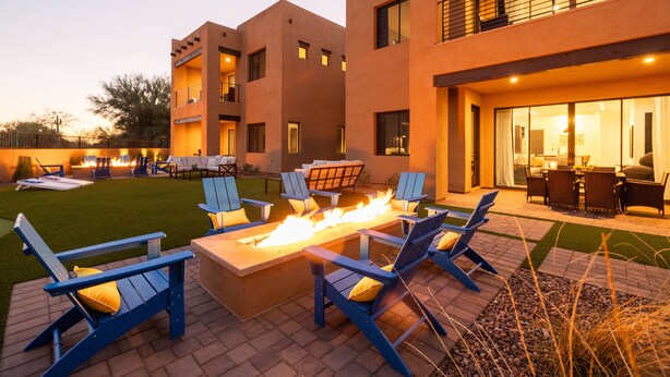 A modern outdoor patio with a fire feature, blue chairs, and a dining area. - Residence 3: The Villas At Troon North (Scottsdale)
