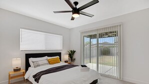 A bedroom with a bed, bedside tables, a ceiling fan, a window with blinds, and a view of the outdoors. - Newly Renovated Home, 1 mi Downtown - 3 BR 2 Bath (Chandler)