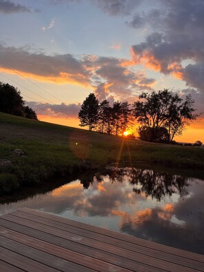 A sunset over a calm body of water with a wooden deck in the foreground. - Willy Cabin

 (Dansville)