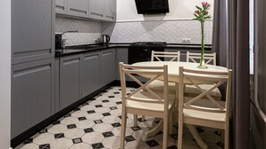 Una cocina con gabinetes grises, una estufa negra y una mesa de comedor con sillas.