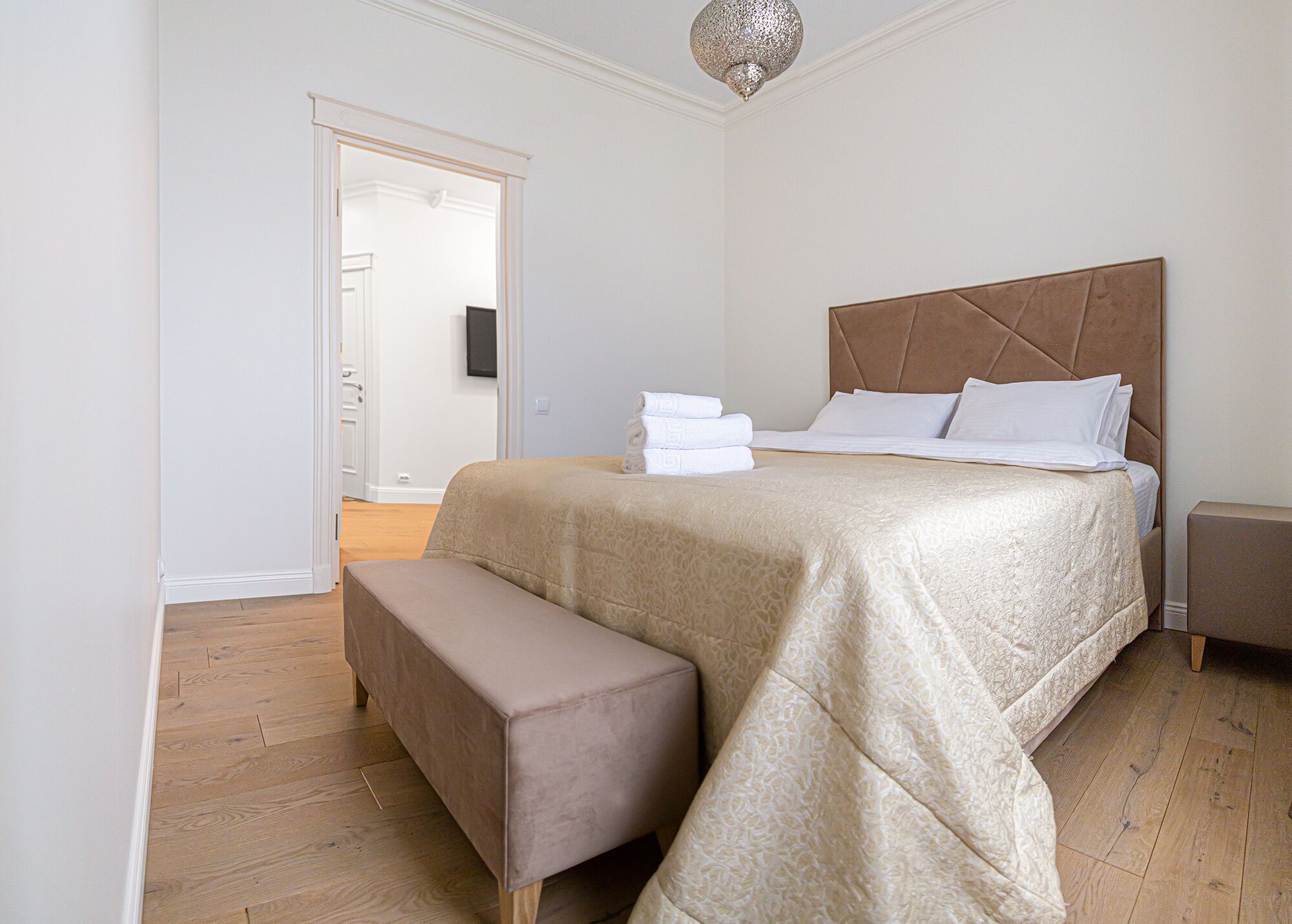 A neatly arranged bedroom with a large bed, a bench, and a bedside table.