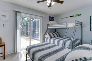 Une chambre avec des lits superposés, un ventilateur de plafond et une fenêtre donnant sur l’extérieur.