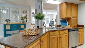 Una cocina con armarios de madera, un lavamanos de acero inoxidable y un lavavajillas.