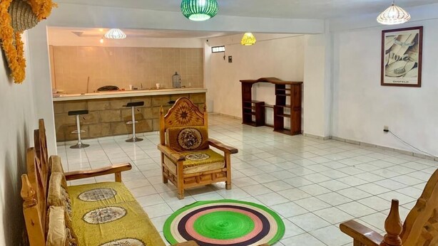 A spacious living area with a wooden sofa, a patterned rug, and a dining table. - Casa Mila Taxco, pueblo mágico, ubicada en Centro Histórico, cerca de todo a pie (Taxco)