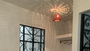 A room with a patterned bedspread, a decorative window with a metal design, and a hanging light fixture casting patterned shadows. - Casa Mila Taxco, pueblo mágico, ubicada en Centro Histórico, cerca de todo a pie (Taxco)