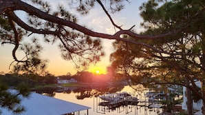 A waterfront property with a dock, boats, and a house with a covered area. - Amazing view of Grand Lagoon and Walk to Beach (Panama City Beach)