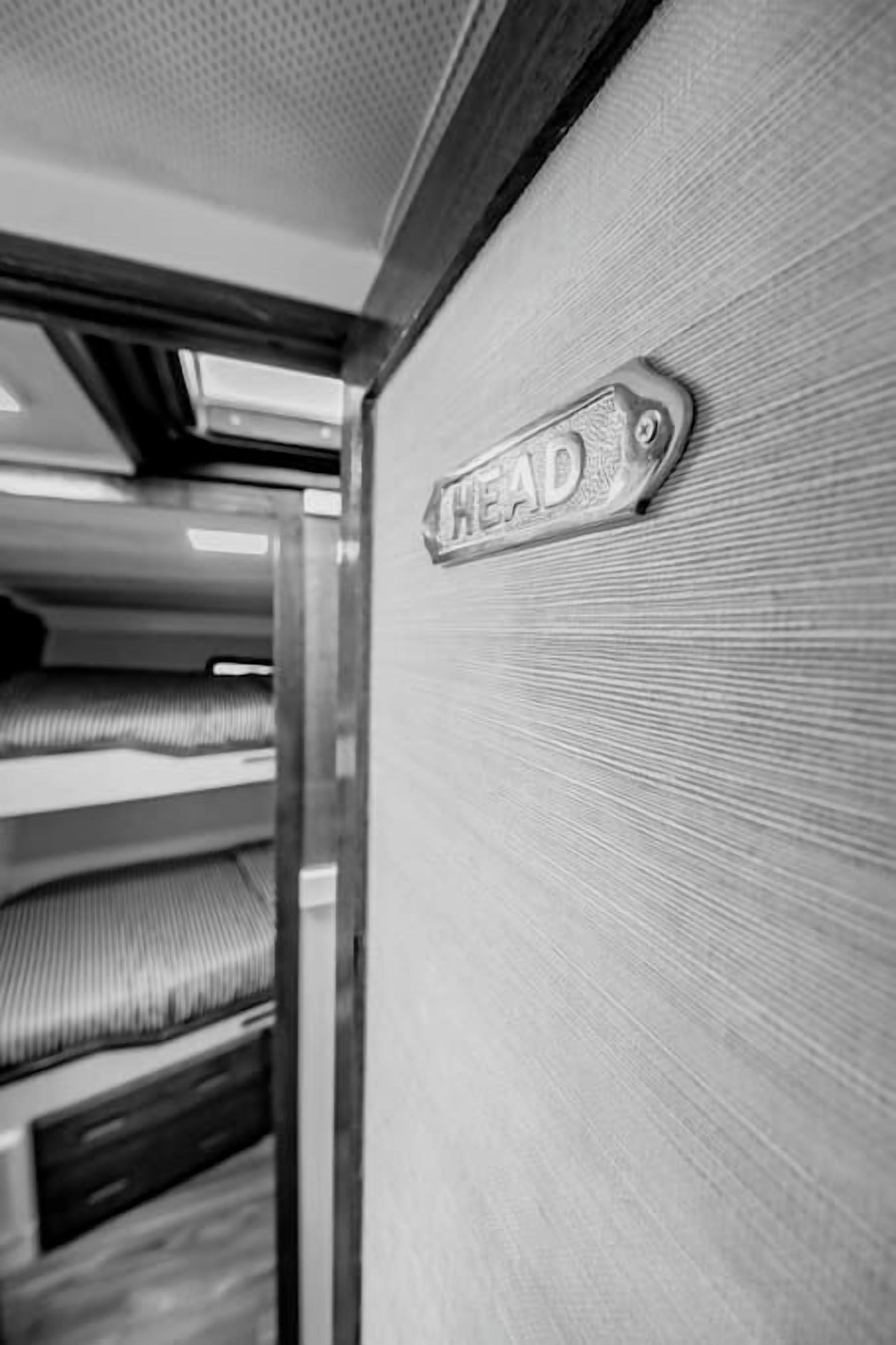 A metallic sign with the word "HEAD" on a textured wall, likely indicating the direction to the headrest or a similar feature.