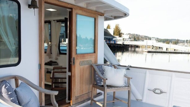 A boat deck with a wooden bench, a small table, and a door labeled "Welcome".
