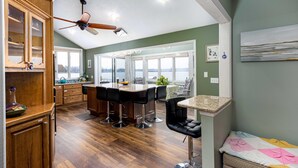 Een moderne keuken met houten kasten, een centraal eiland met barkrukken en een plafondventilator.