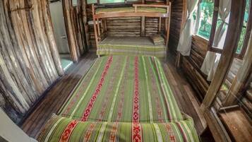A rustic cabin with a bunk bed, wooden walls, and a window with curtains.