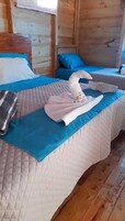 Habitación de cabaña de madera con cama, ropa de cama azul y una toalla doblada con un logotipo.