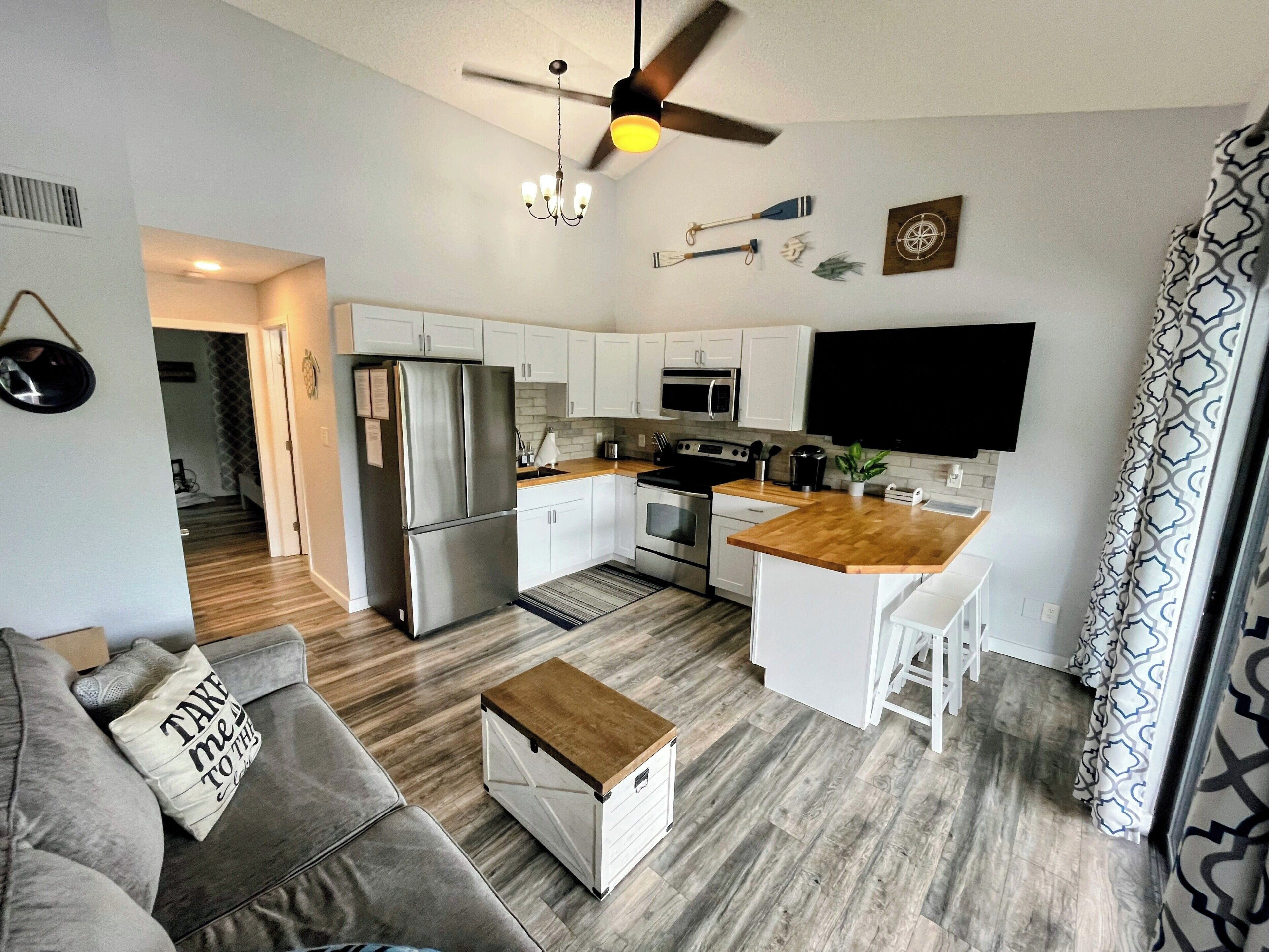 A modern kitchen with white cabinets, stainless steel appliances, and a wooden countertop.