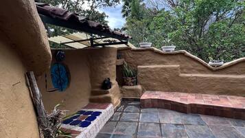 Un espace patio avec des carreaux de pierre, un mur rustique agrémenté d’un carrelage décoratif et des plantes en pot.