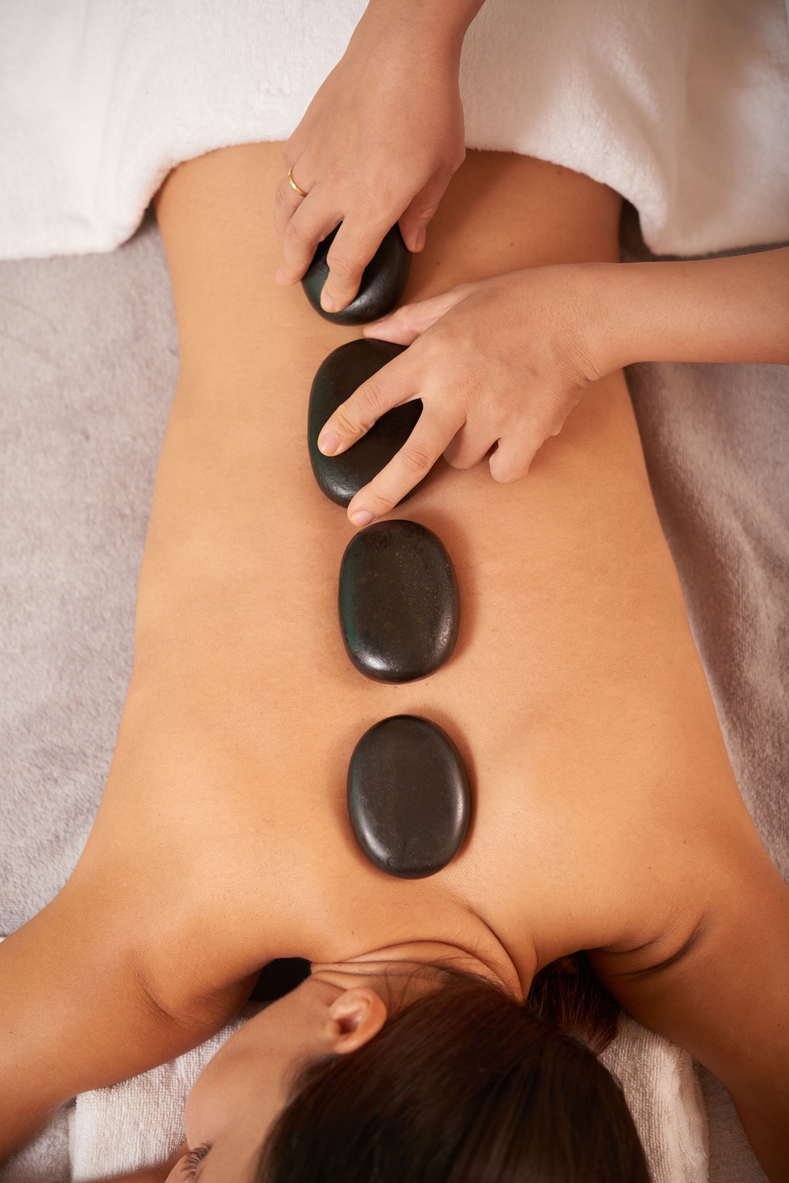 A person receiving a back massage with stones.