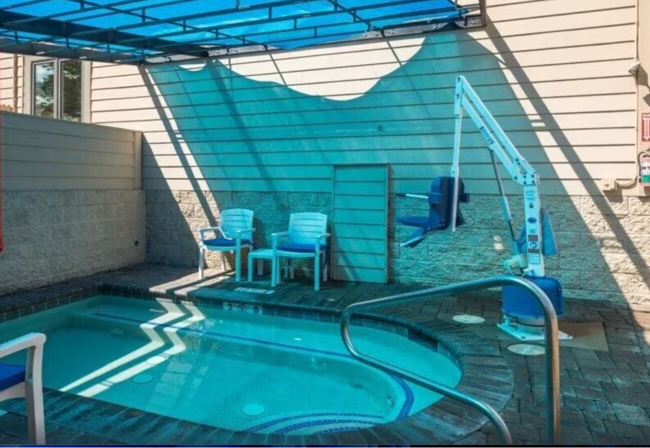 Une piscine recouverte d’une bâche bleue, avec une échelle et quelques chaises.