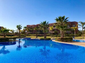 Relax by the resort's clear blue pool surrounded by lush palm trees and greenery.