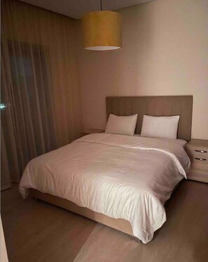 Relax in this serene bedroom with a large bed, wooden headboard, and stylish nightstand.